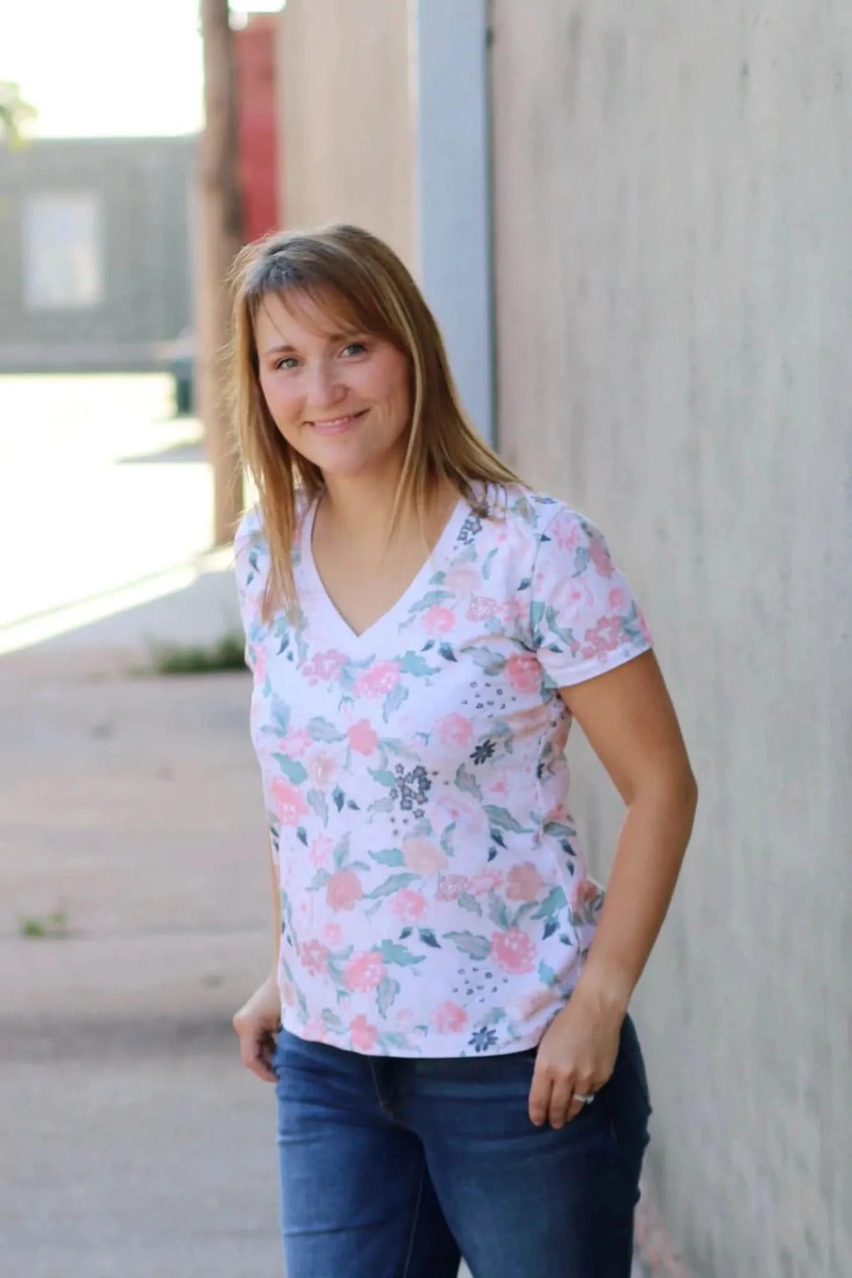 Blush flowers floral print fabric on a woman modeling a pink V-neck T-shirt.