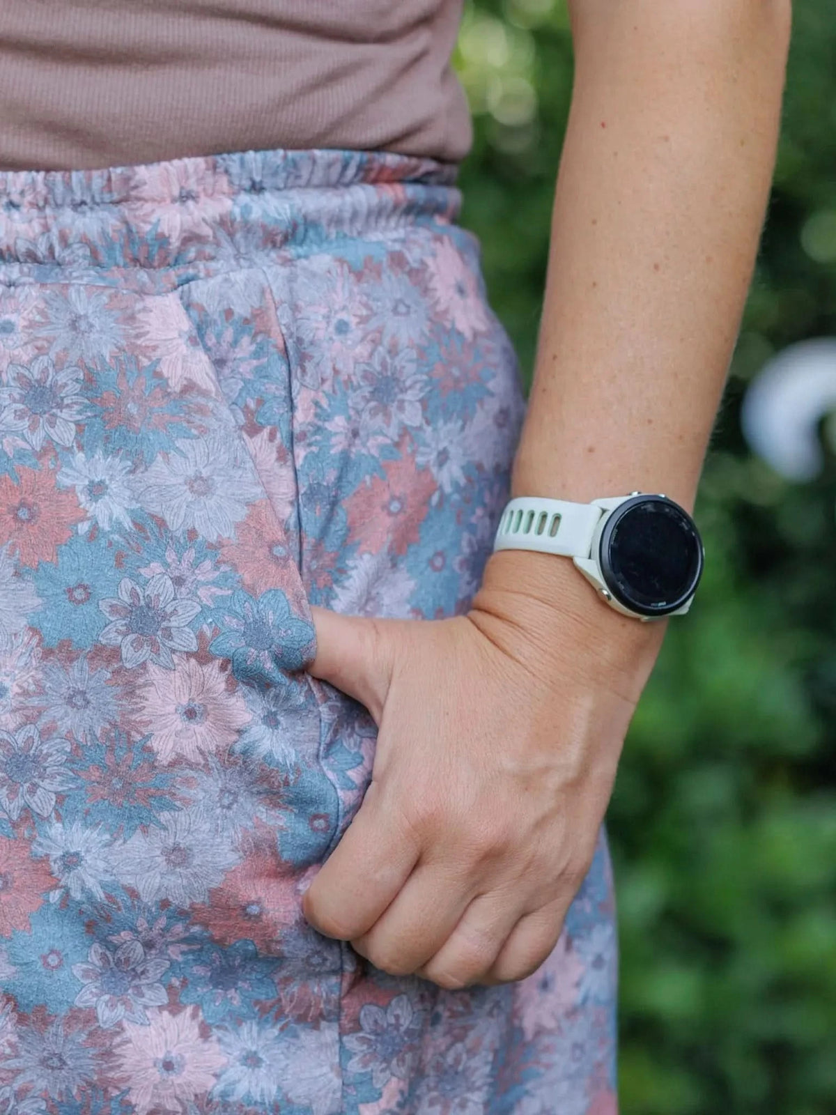 Close-up of blue and pink floral print fabric on pants, showing autumn blooms pattern.
