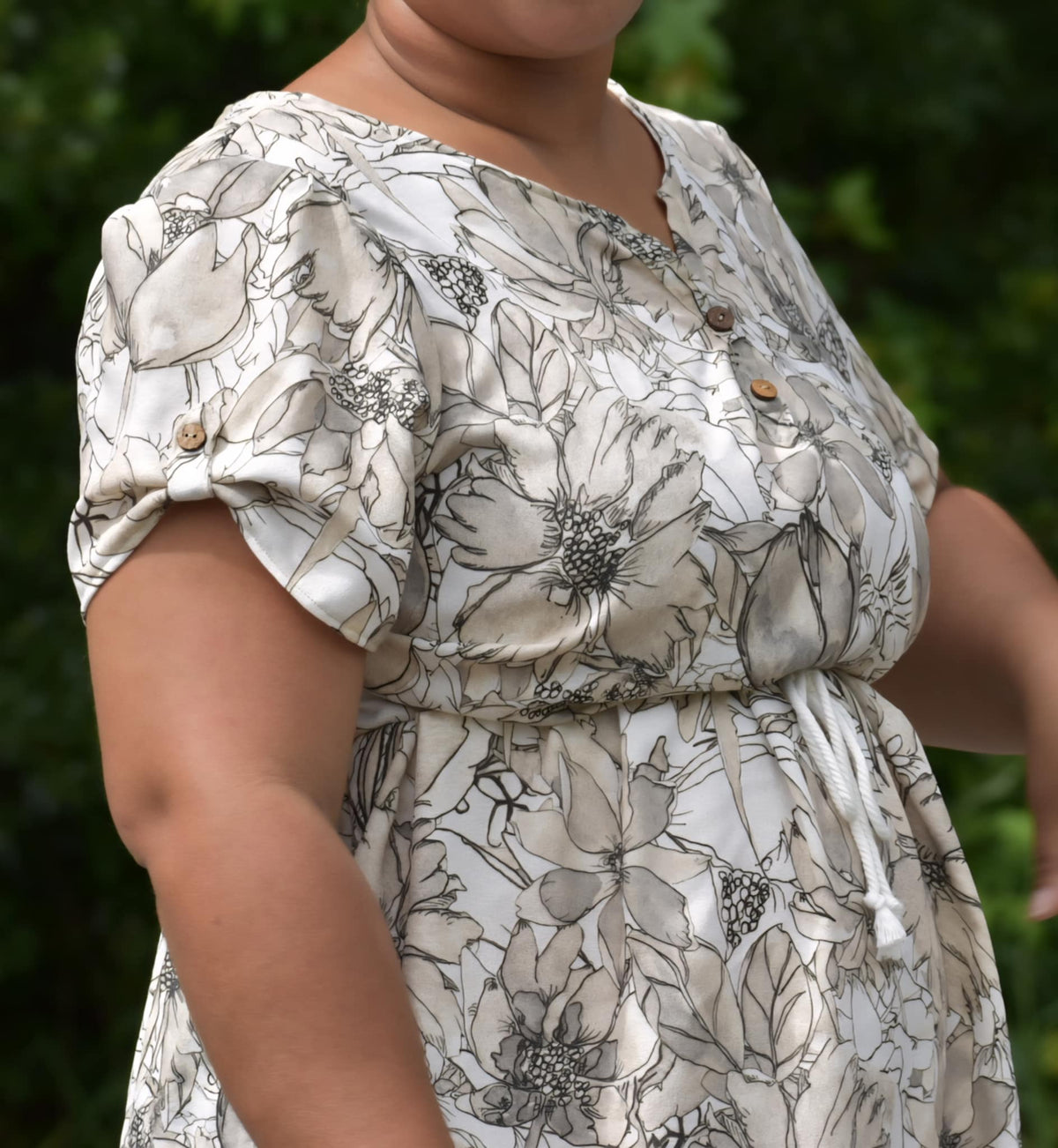 A person wearing a sepia sketch floral print dress with a drawstring waist.