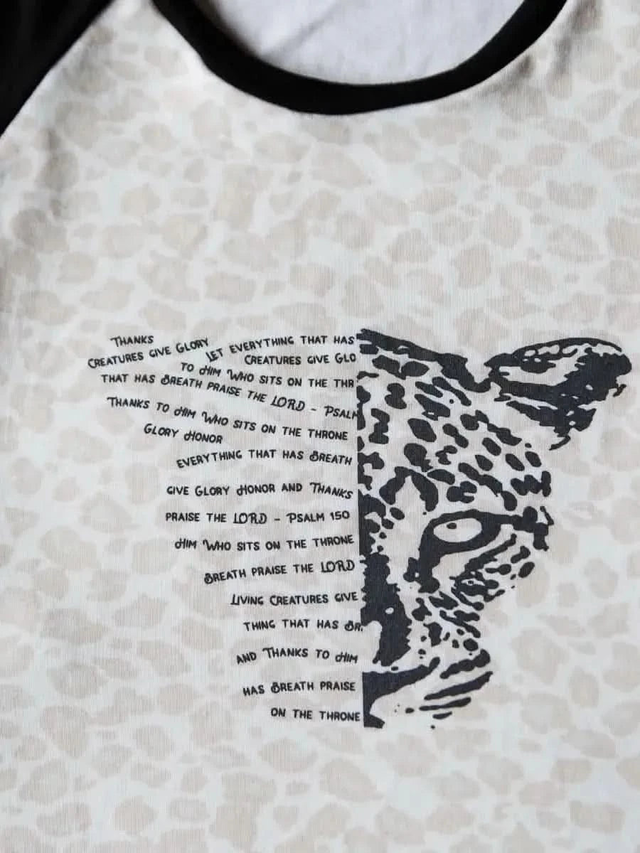 White fabric panel with black leopard head and faith-based text "Creatures Give Glory.