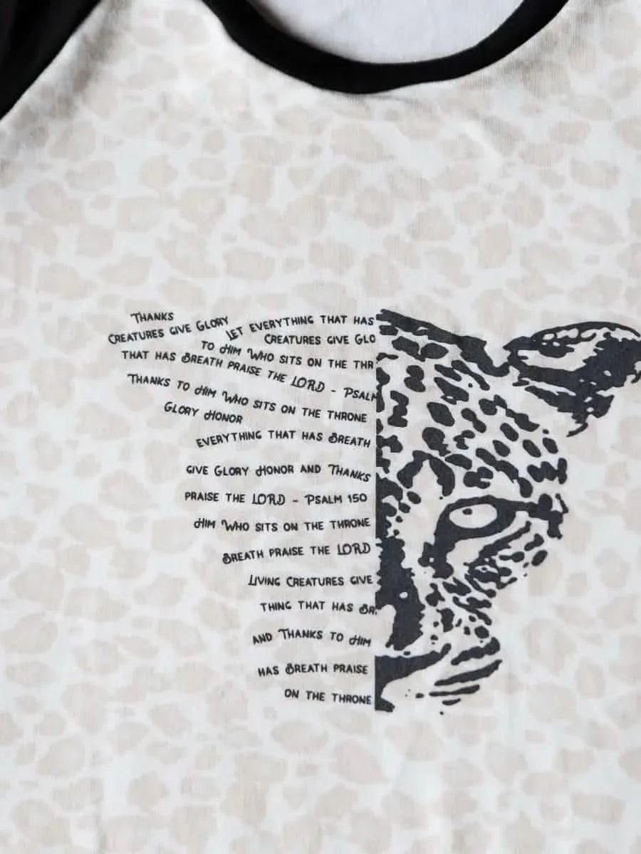 White t-shirt with black leopard print and overlaid Bible verse text.