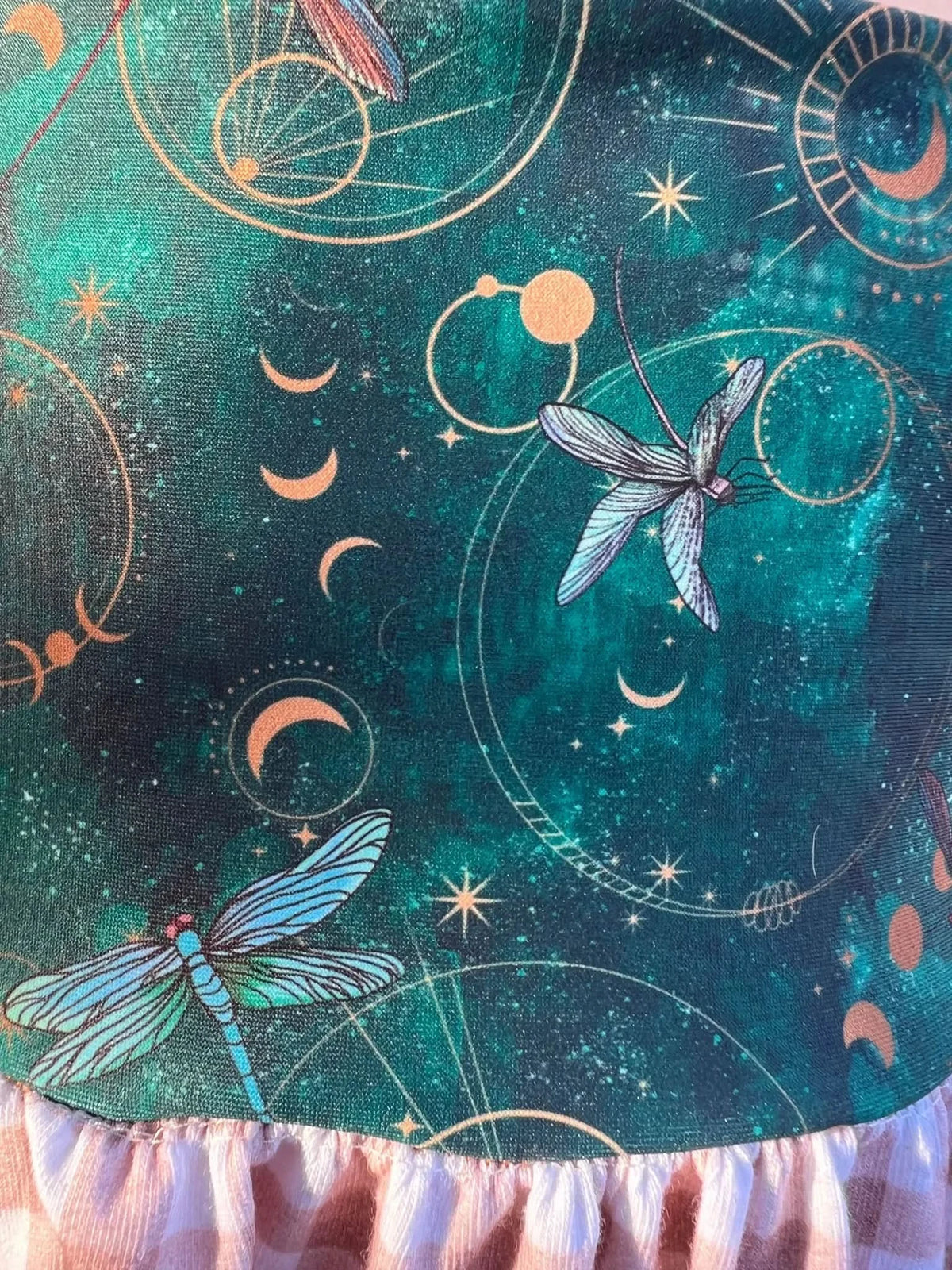 Celestial dragonfly print fabric with gold moons, stars, and circles on green background.