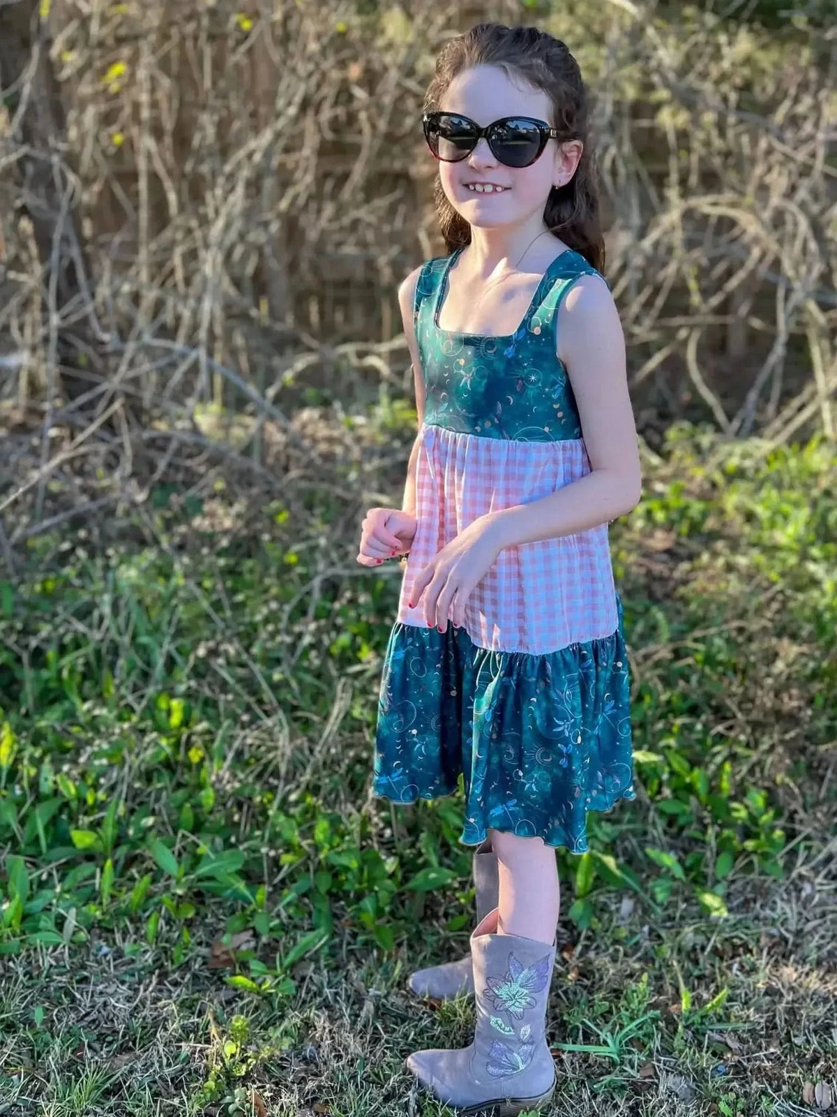Girl in tiered dress made from celestial dragonflies fantasy print fabric, outdoors.