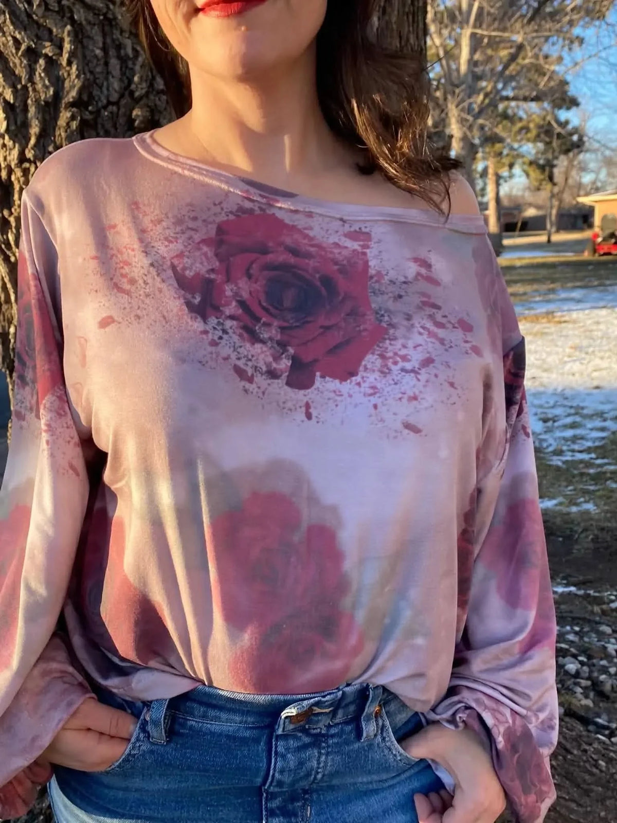 A woman wears a long-sleeved shirt with a shattered rose floral print.