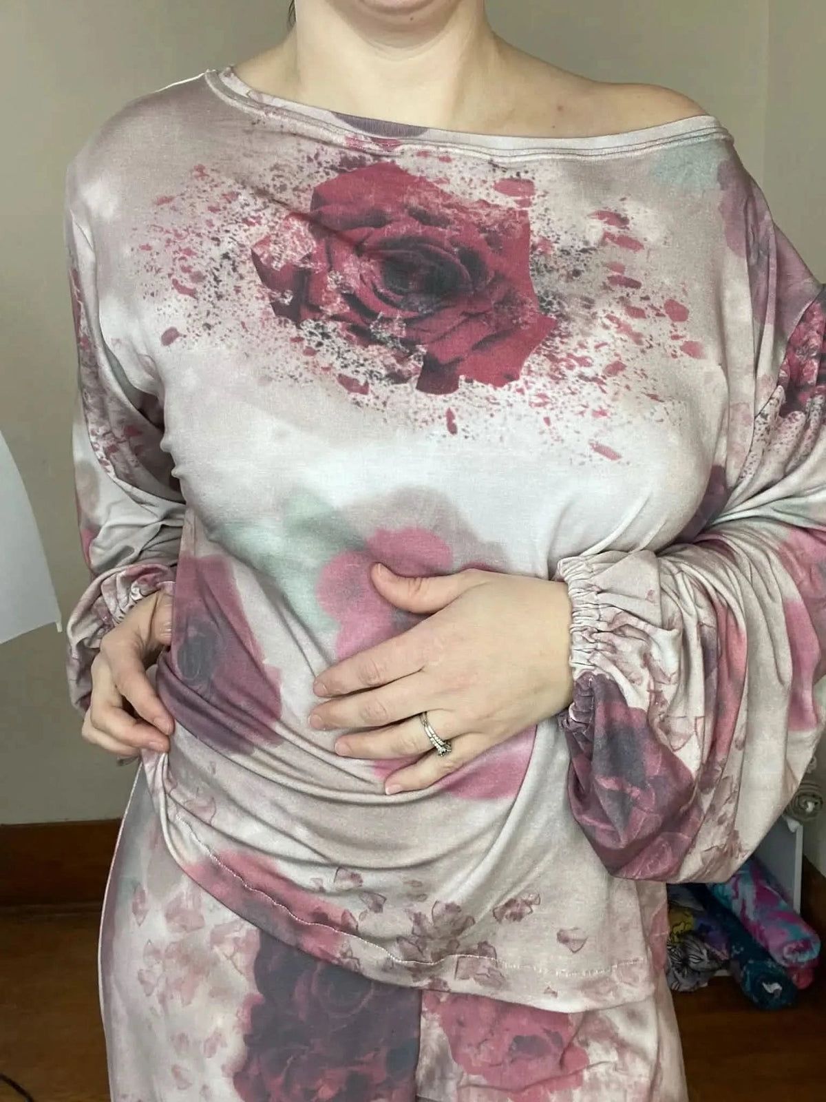 A person wears a long-sleeved top and pants with a shattered roses floral print.