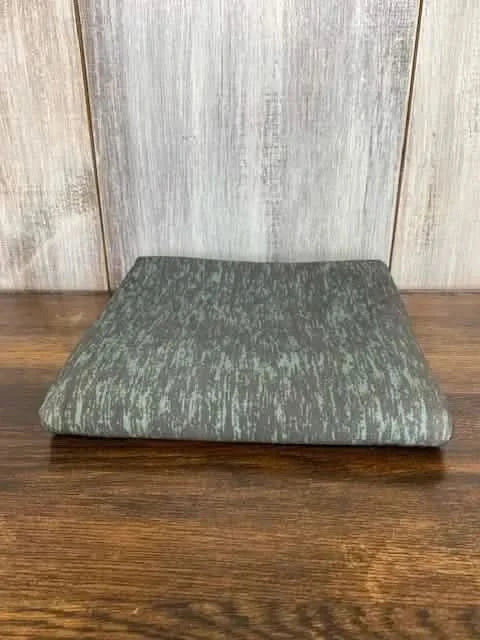 Dark green heather fabric swatch displayed on a wooden surface.
