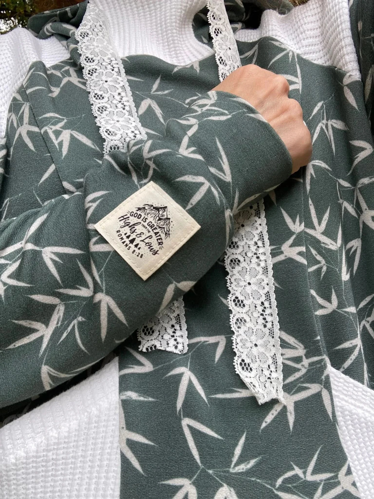 Green bamboo leaf print fabric with white lace trim on a garment sleeve.