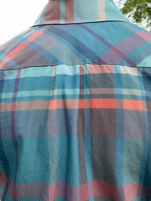 A close-up of a teal, blue, coral, and brown plaid fabric.