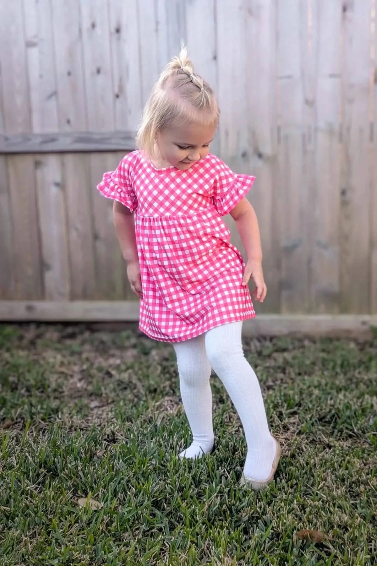 Close-up of hot pink gingham fabric with checkered pattern on a sewn dress.