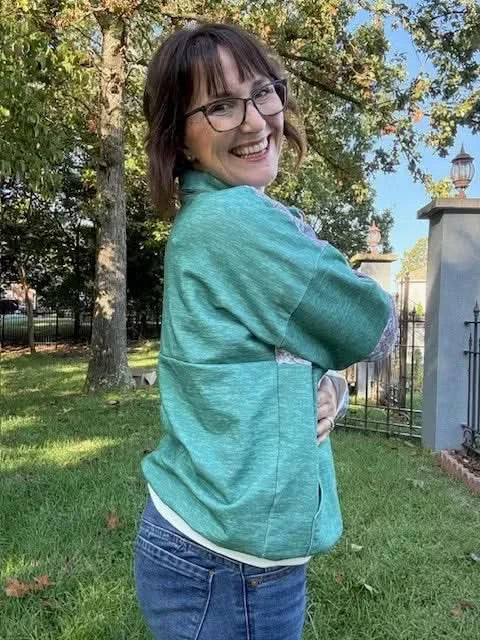 Side view of a woman modeling a grass green heathered fabric cardigan outdoors.