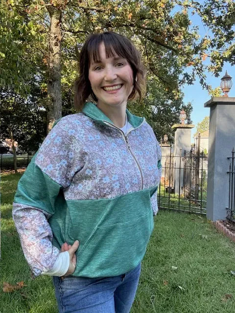 Woman modeling a grass green heathered fabric hoodie with floral patterns outdoors.