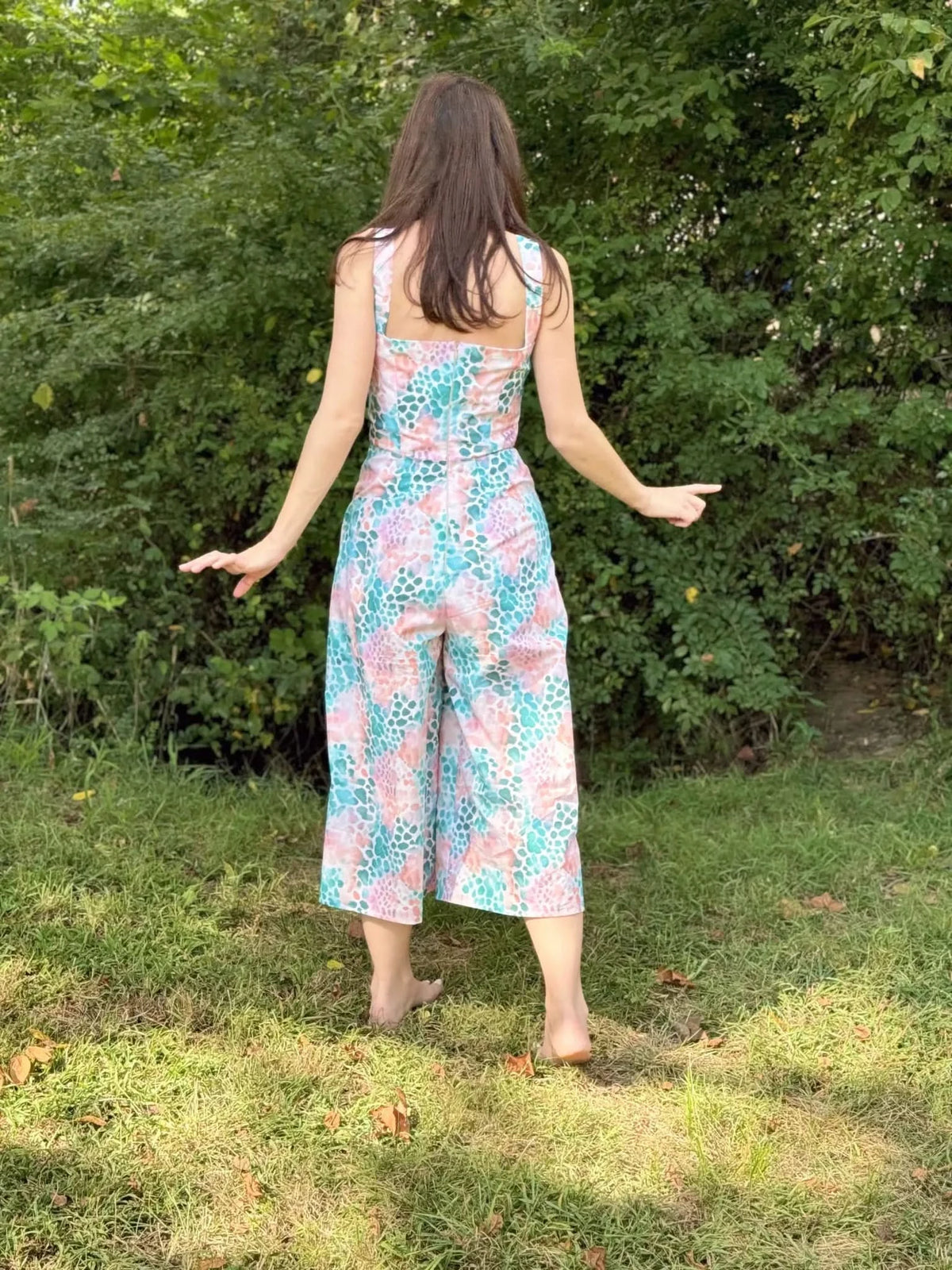 Vibrant abstract print fabric in pink and green tones, shown as a back-view wide-leg jumpsuit.