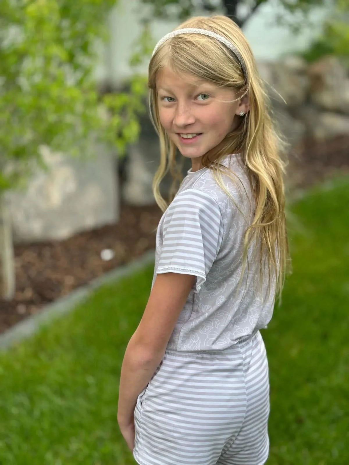 Girl wearing gray striped jumpsuit made from WayMaker Fabrics fabric, outdoors.