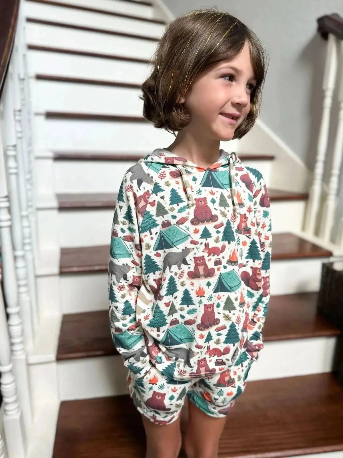 Child's hoodie and shorts set in cream fabric printed with colorful camping bears and woodland animals.