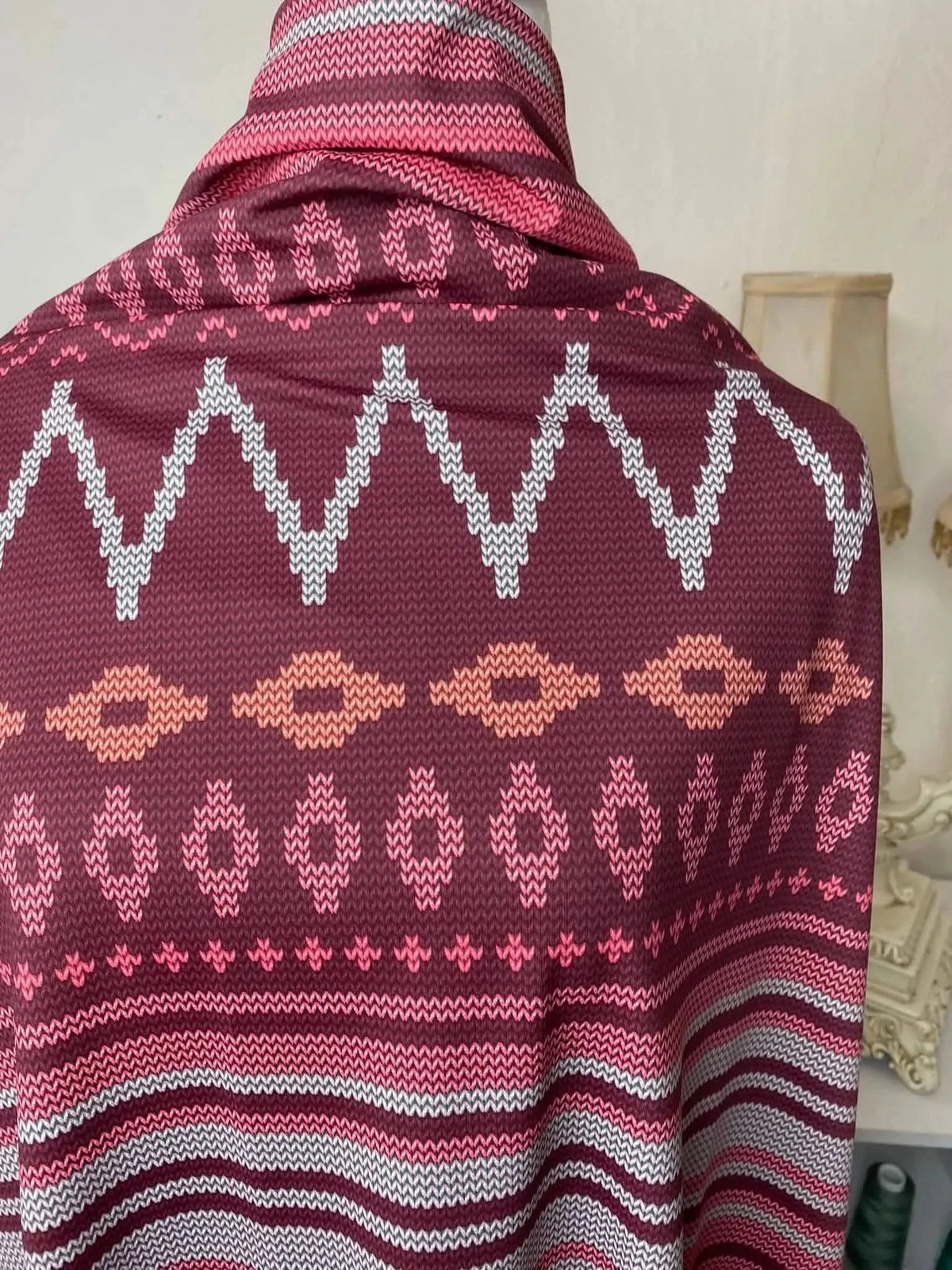 Pink abstract fabric with zigzag and diamond patterns in pink, maroon, and orange tones.