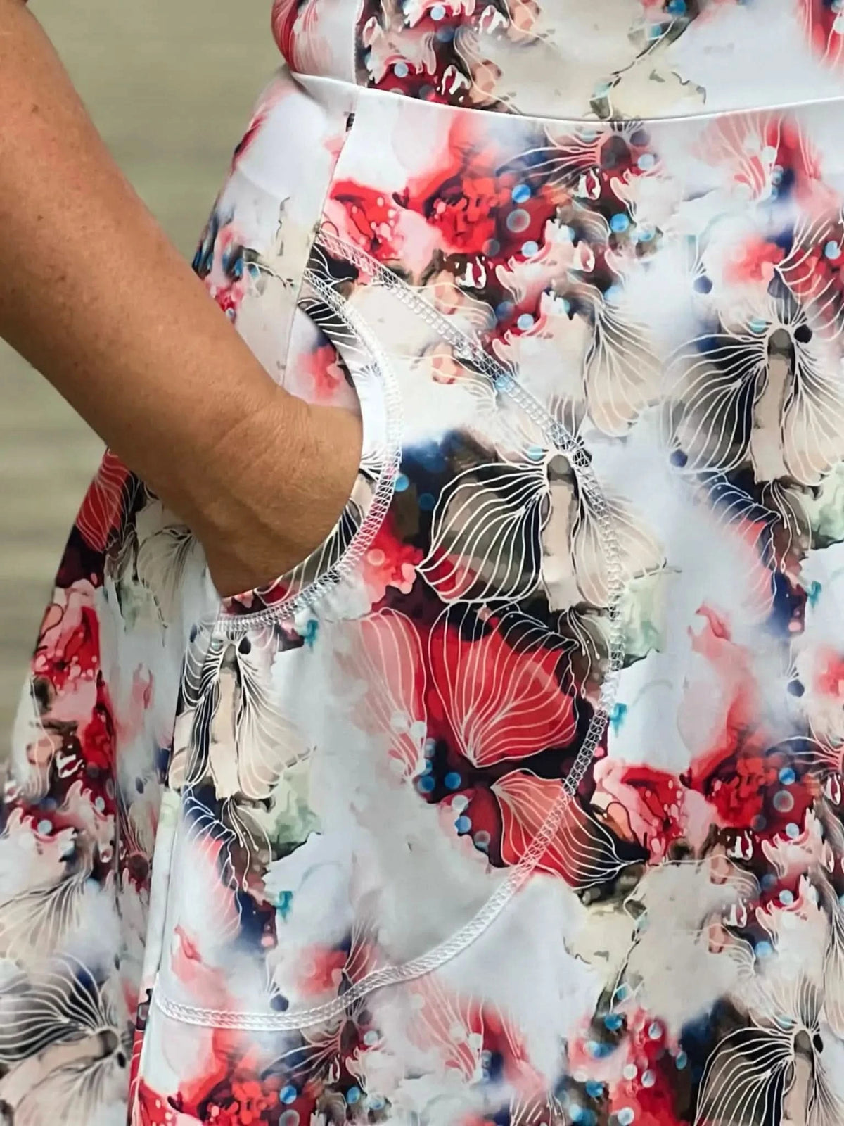 A person's arm in a floral skirt with a pocket.
