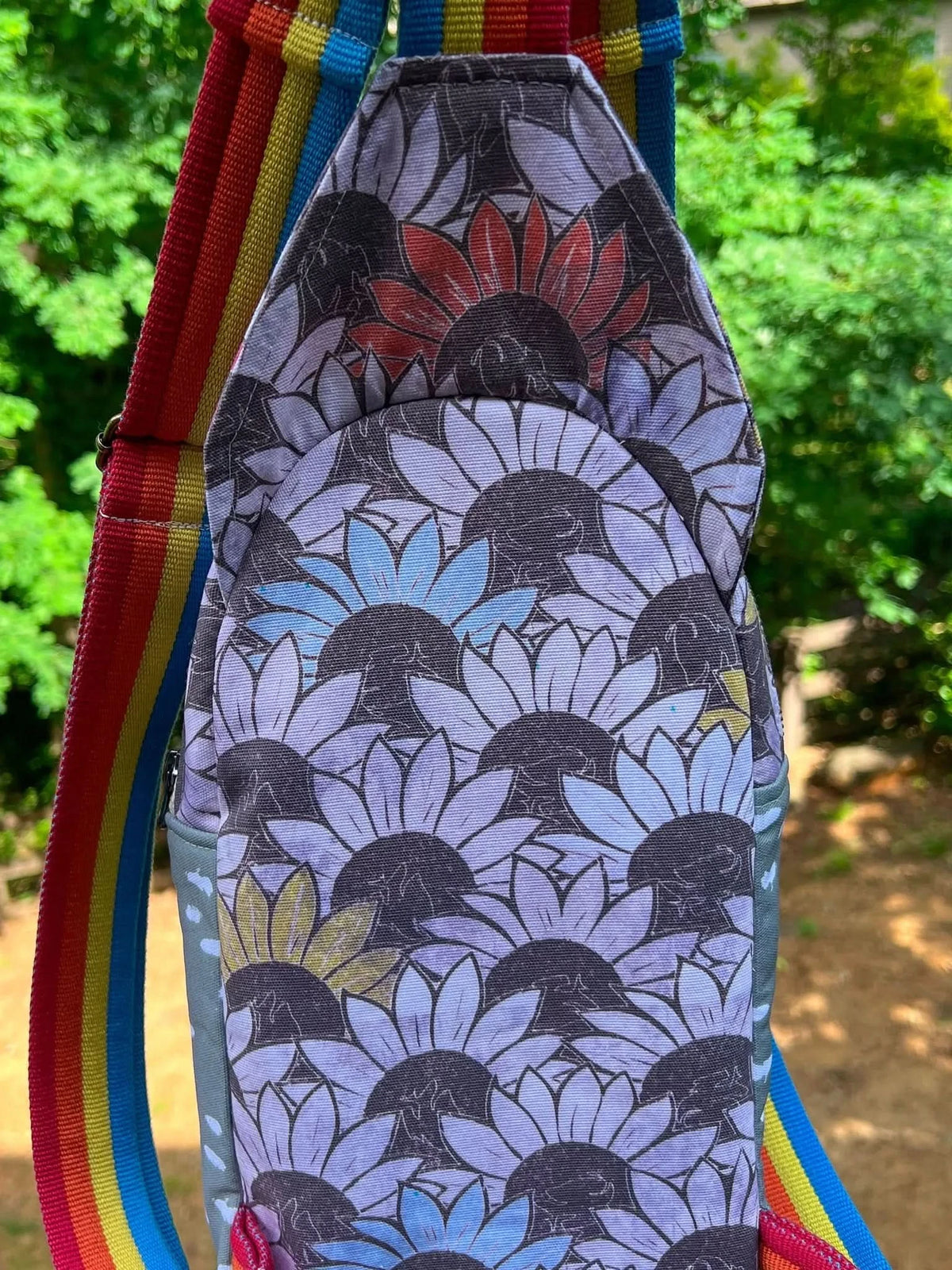 Vibrant sunflower print fabric with multicolored floral pattern on gray background.
