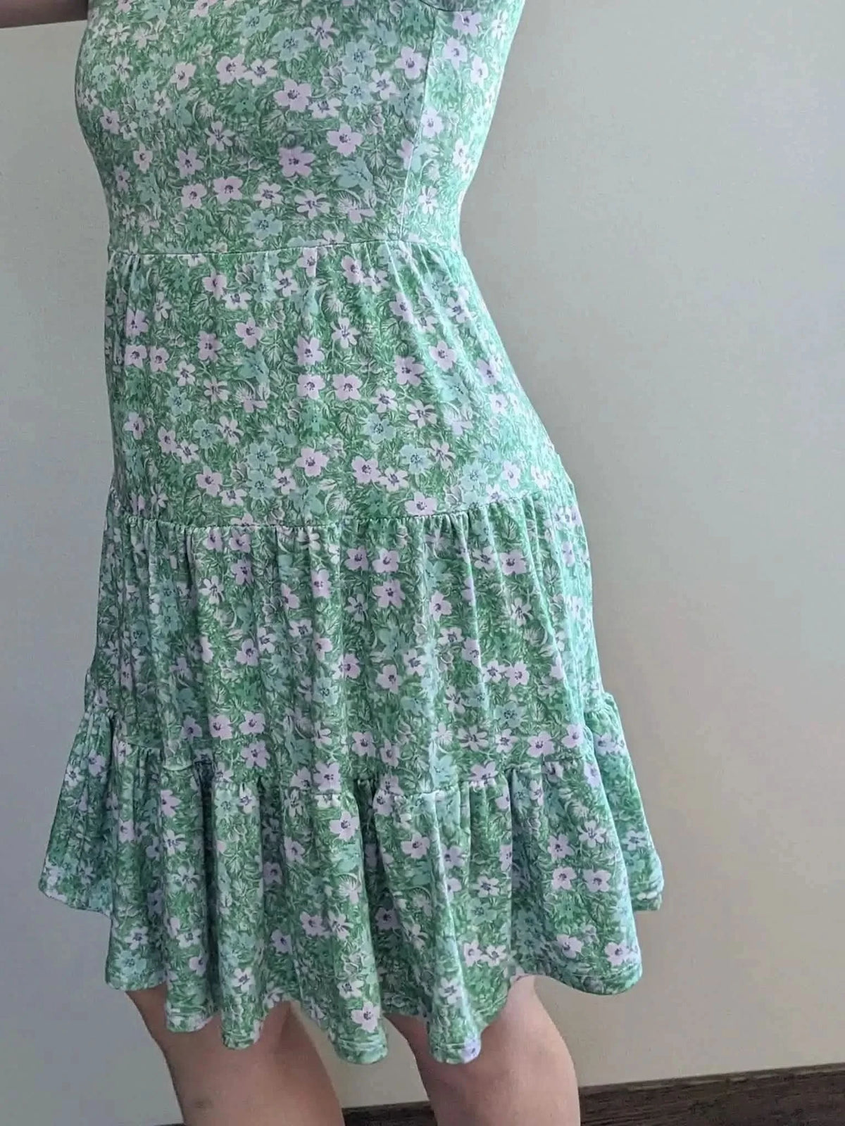 A person models a green floral print tiered dress.