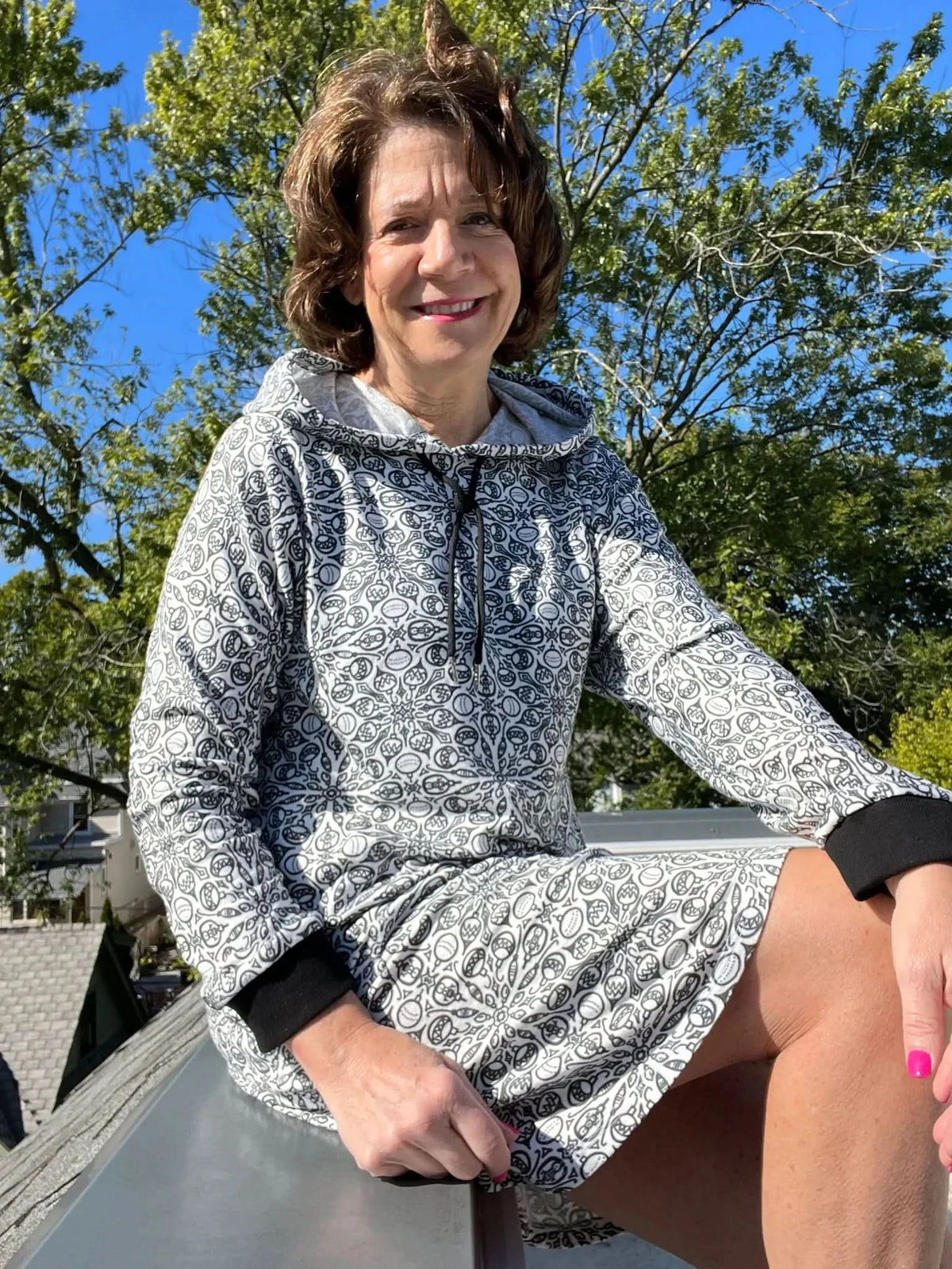 A woman wears a black and white patterned hoodie dress with black cuffs.