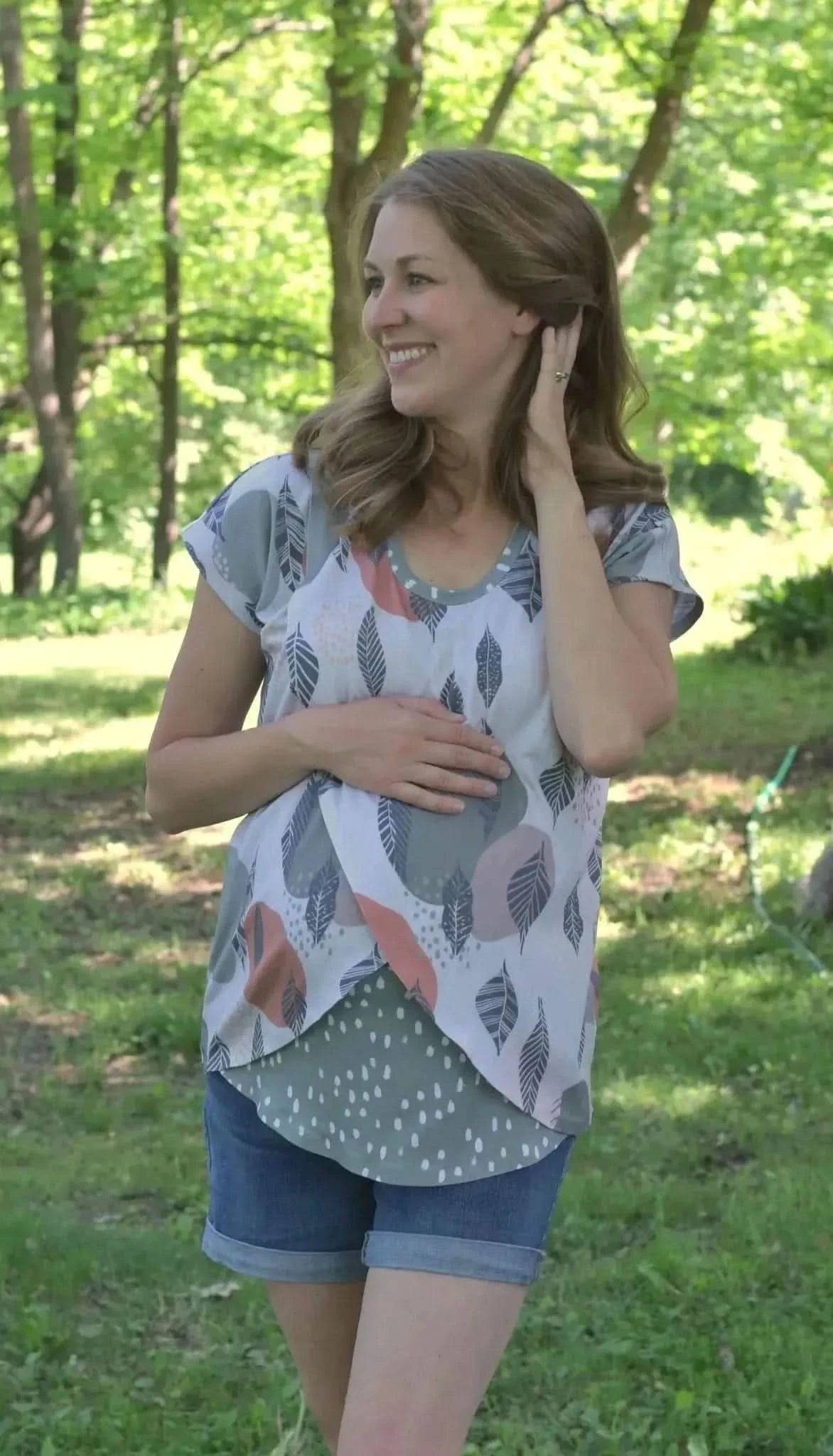 Mod Leaves Fabric in green leaf pattern print, shown on a model wearing a maternity top and shorts outdoors.