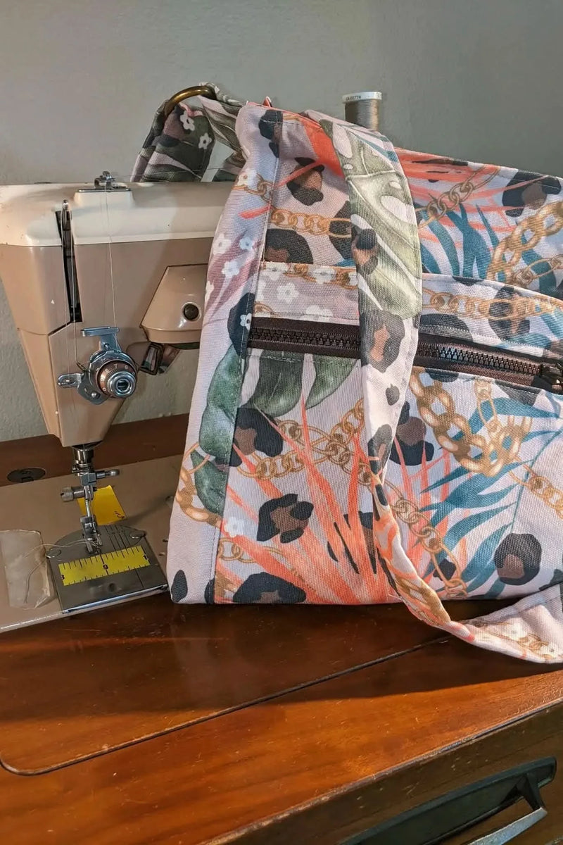 Luxe leopard print fabric with green palm leaves on a sewing machine.