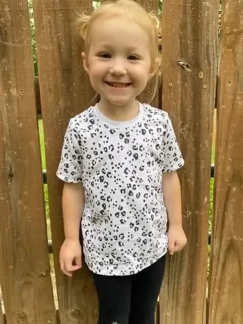 White cotton children's t-shirt with black leopard print pattern.