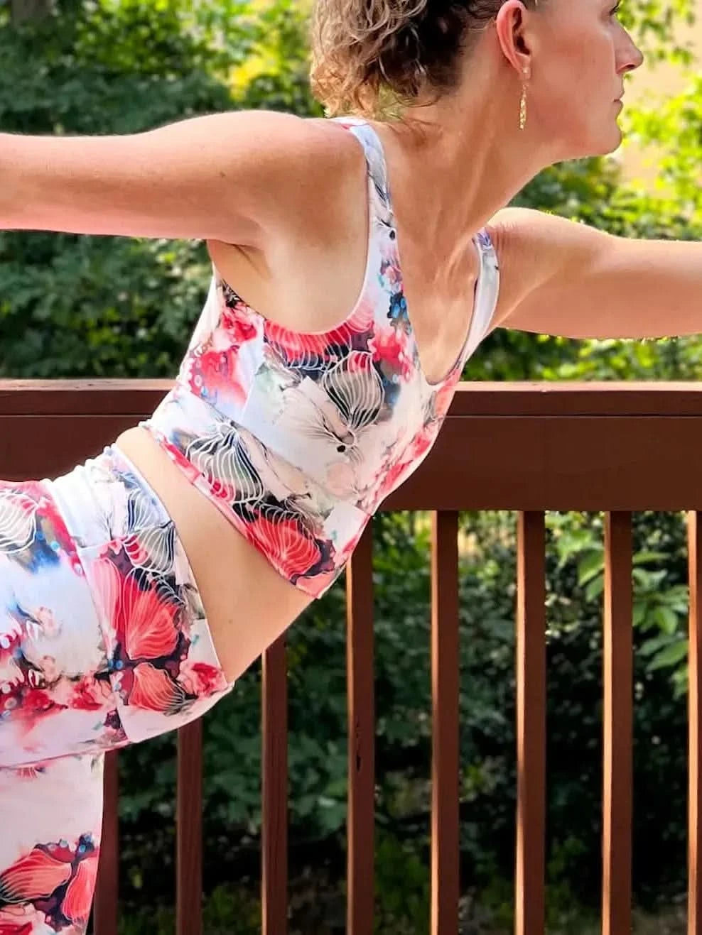 A woman wears a floral sports bra and leggings with red, white, and blue flowers.