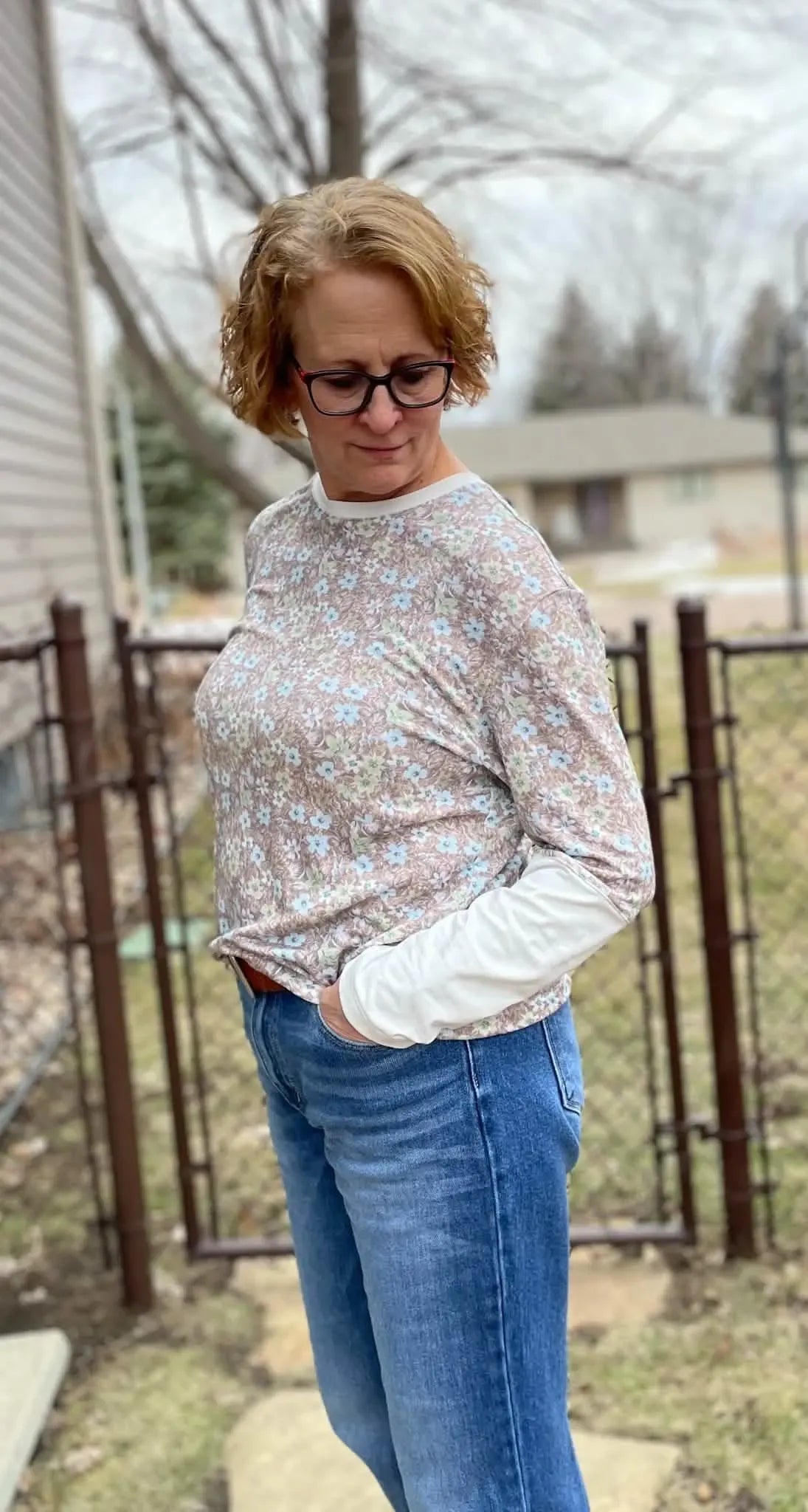 Woman wearing a brown botanical print long-sleeve shirt with blue jeans.