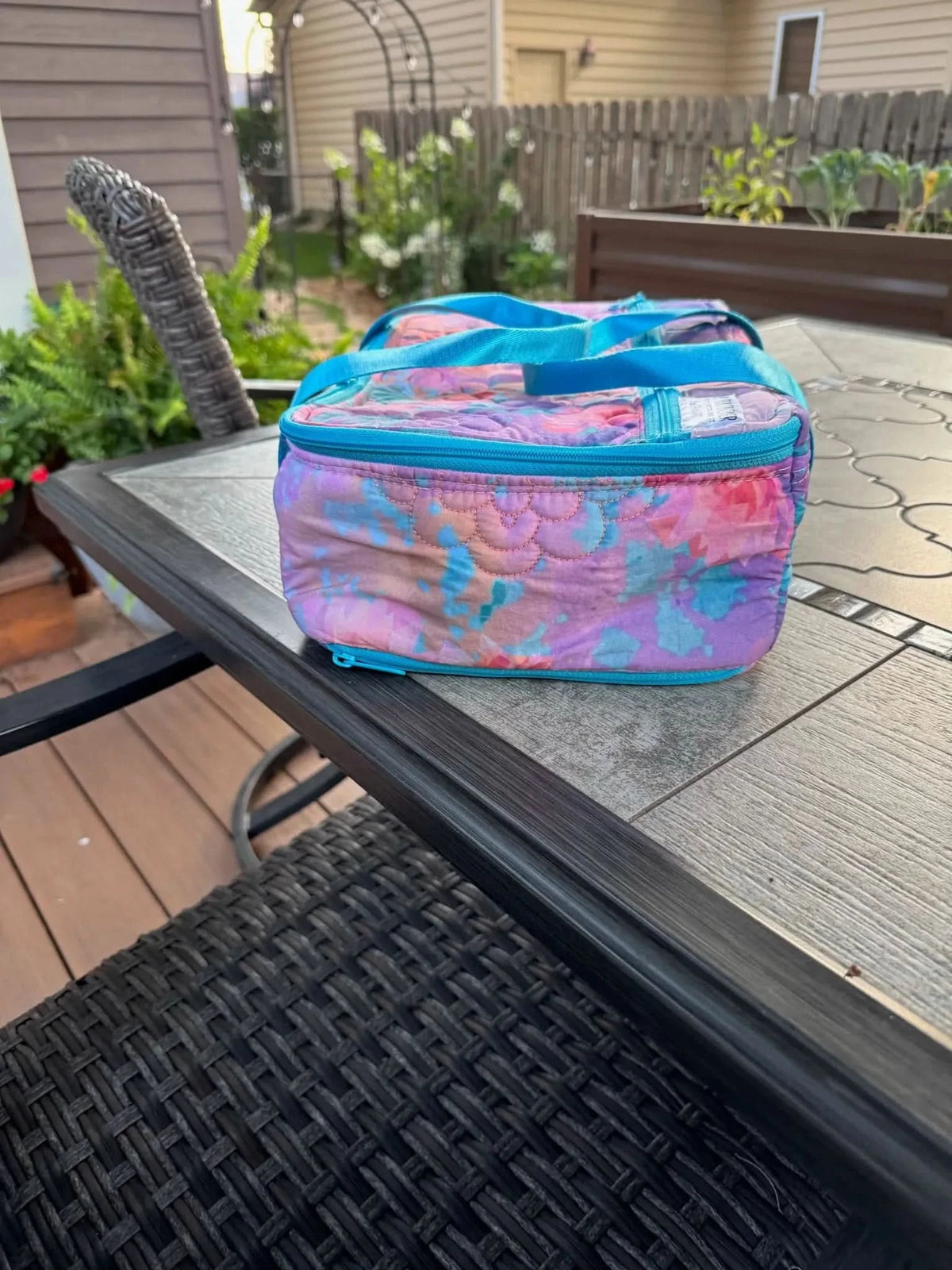 Purple fabric with glass flower pattern, shown as a lunch bag on a patio table.