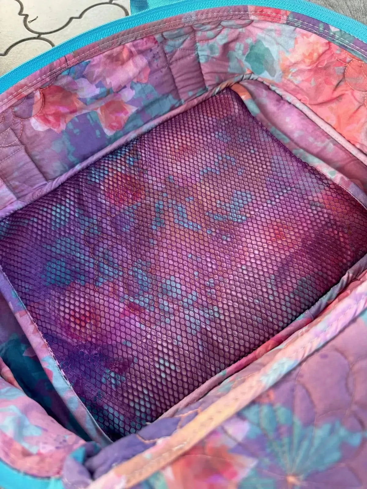 Purple fabric with glass flowers print, showing floral patterns in pink, purple, and blue.