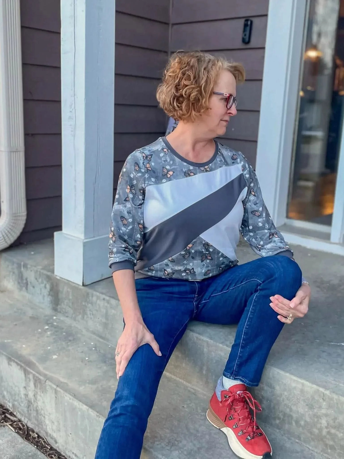 Gray fabric with monarch butterfly print, shown in a woman's three-quarter sleeve top.