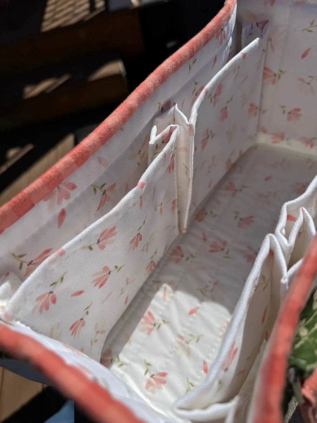 Close-up of floral print fabric with pink spring flowers on white background, used in a sewn organizer.