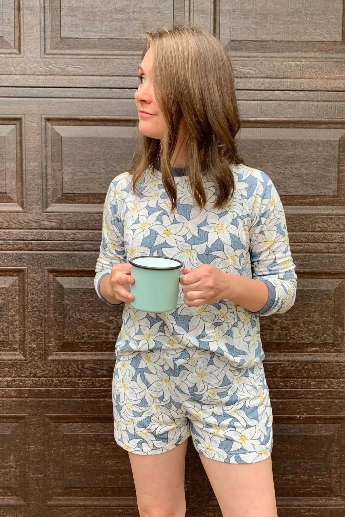 Blue lilies floral print fabric in light blue with white flowers on a model wearing a sweater and shorts.