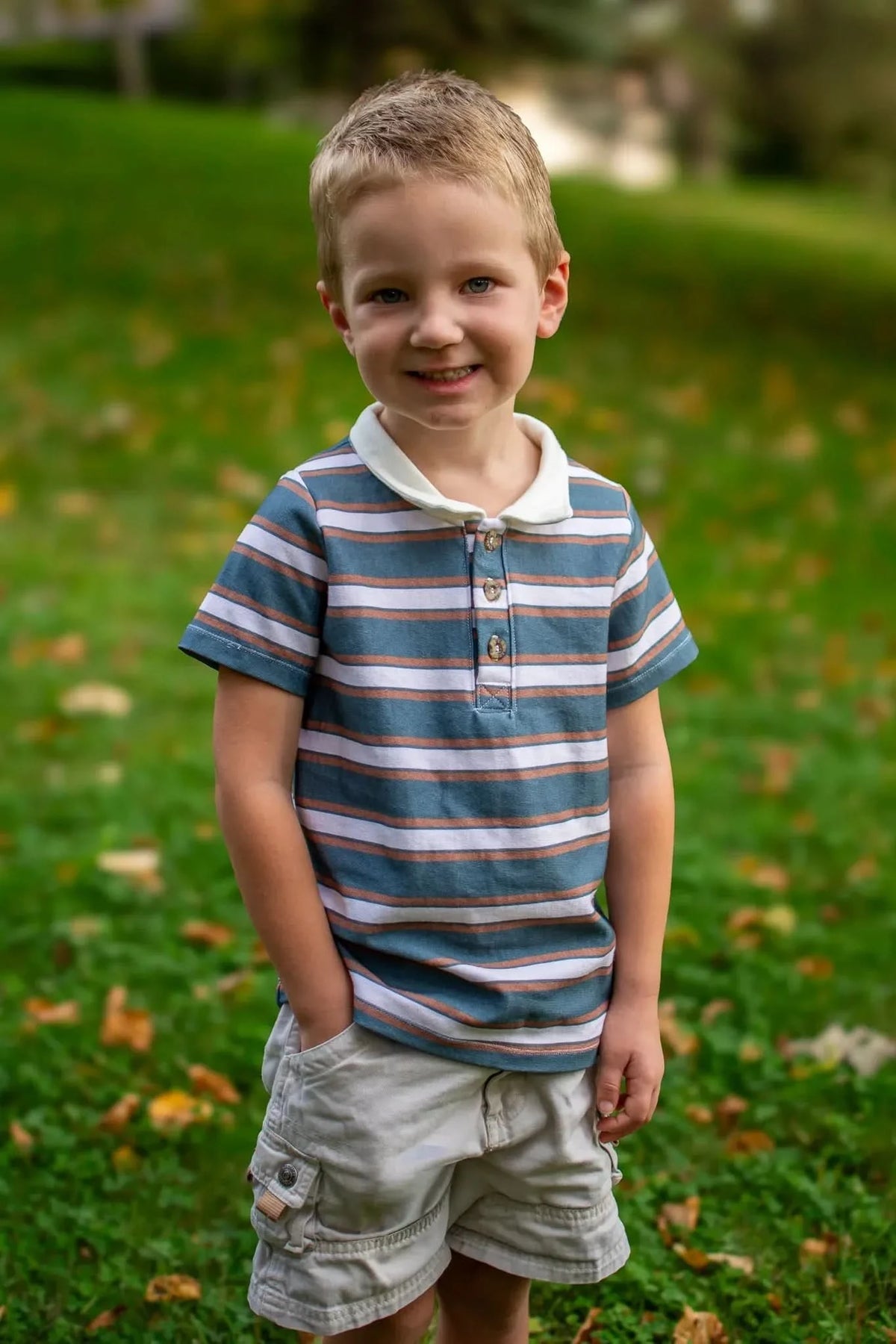 Verdant Stripes striped fabric in green and white, shown as boy's shirt and shorts on grass.