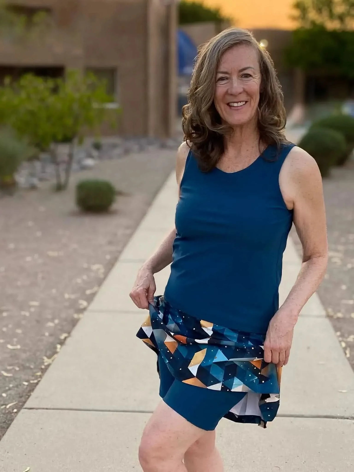 Woman modeling a teal tank top and skirt with celestial blue gold abstract print.