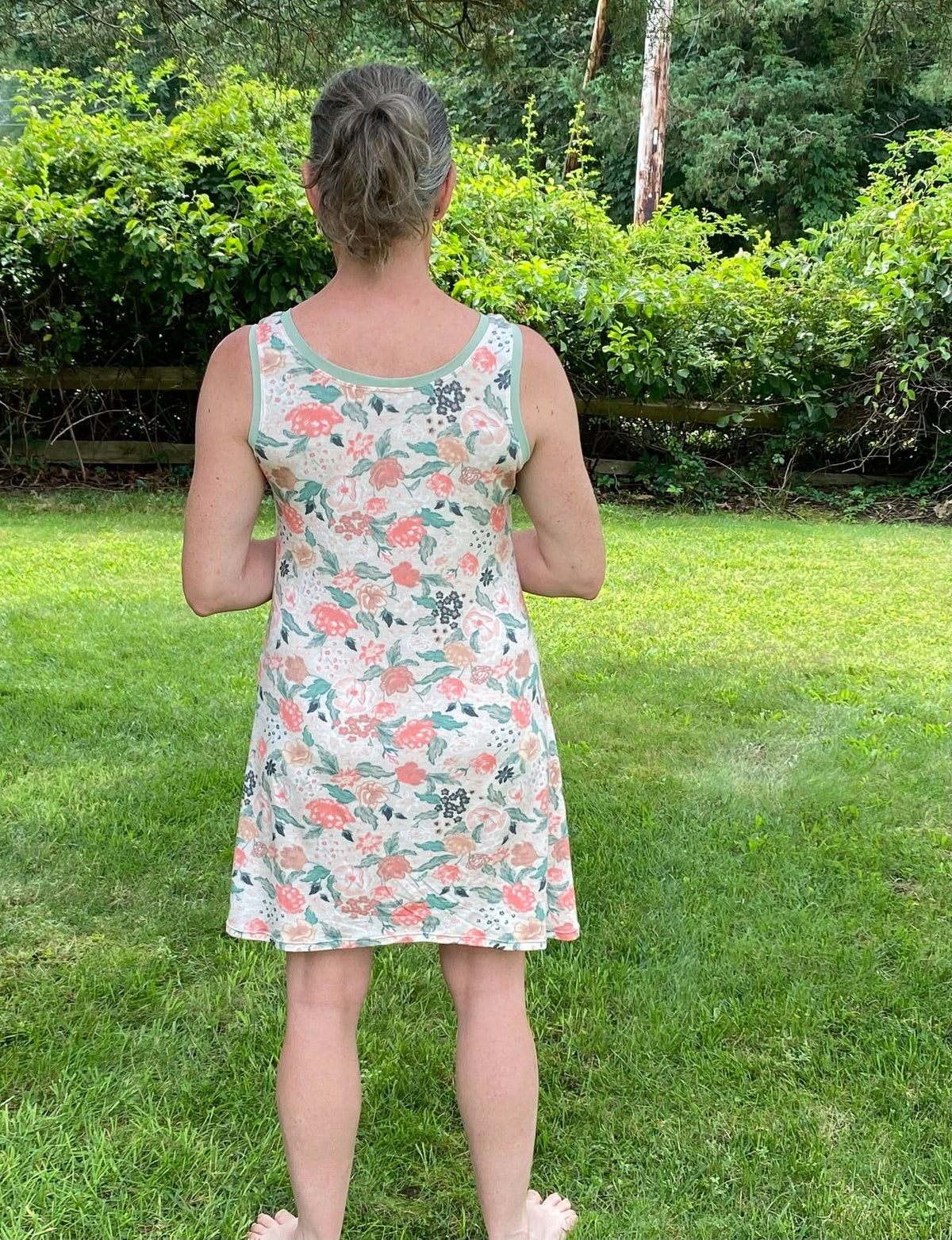 A woman from behind wears a floral dress with a light green trim.