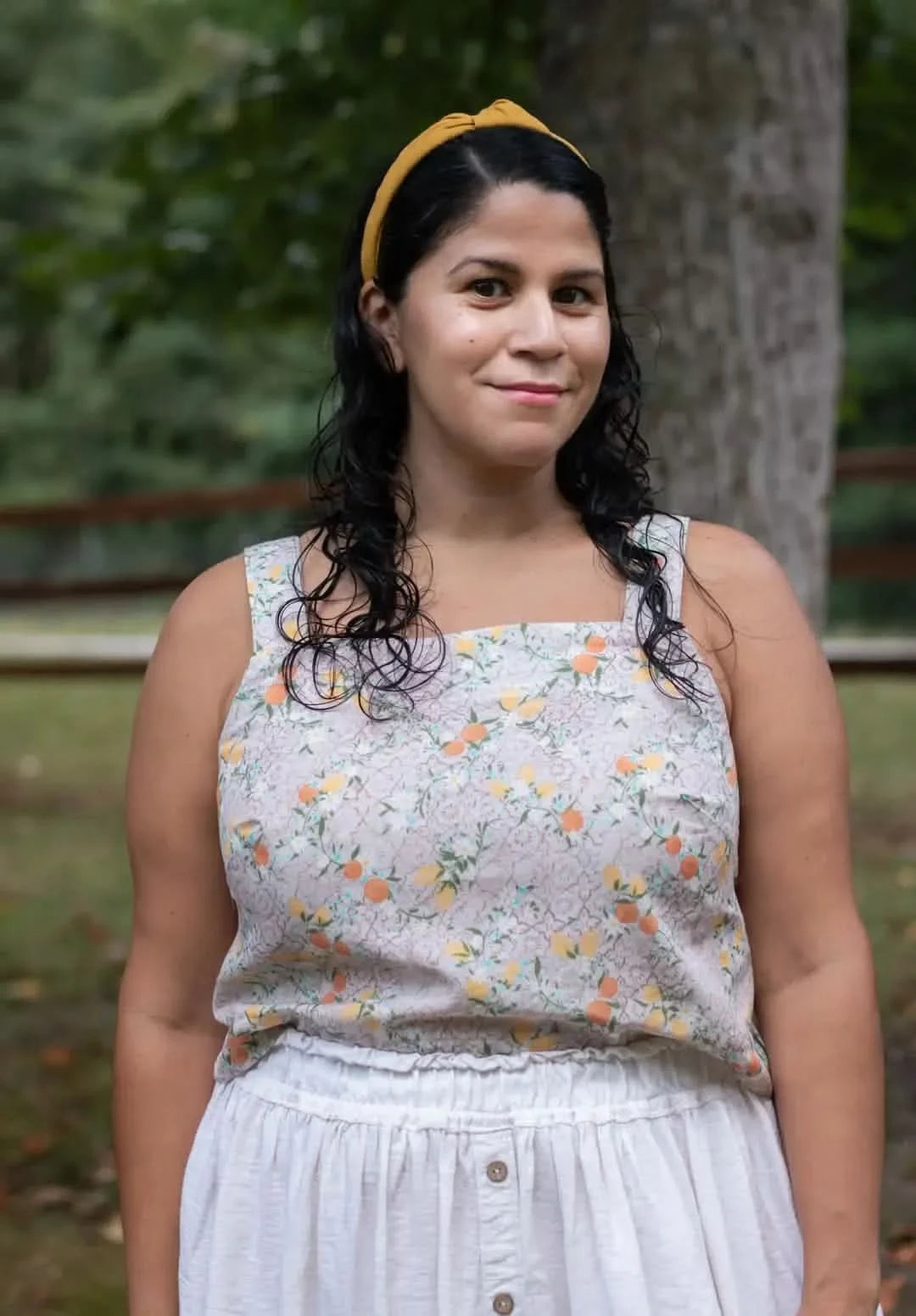 A woman wears a top made from Moroccan Citrus fabric, featuring a vibrant summer print.