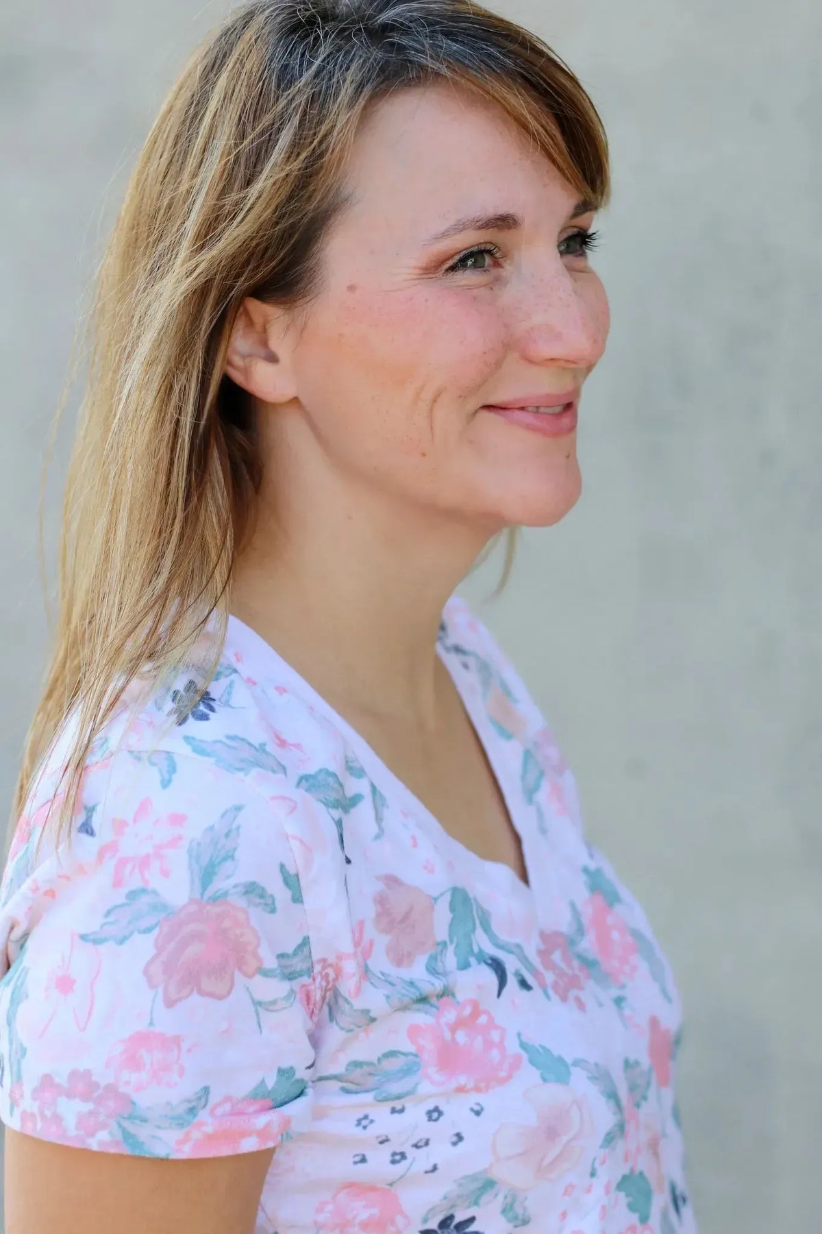 A woman in a white shirt with a blush floral pattern.