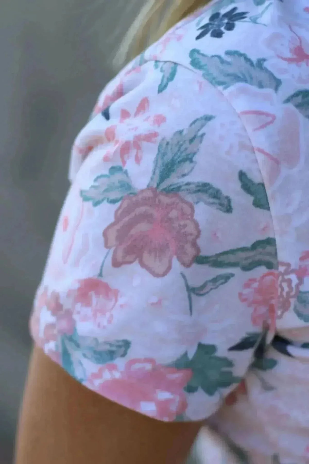 Close-up of a person's arm wearing a shirt with a blush floral print.