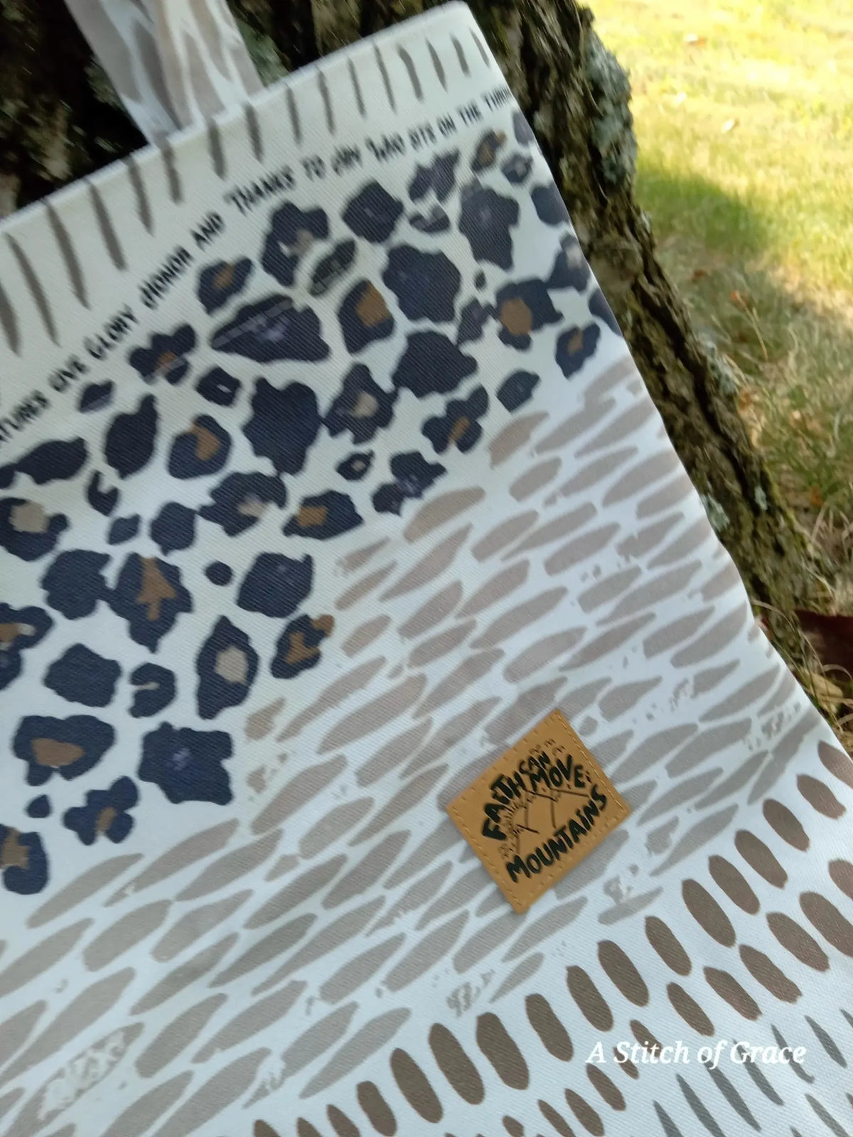 Fabric with leopard print and abstract patterns, featuring a "Faith Can Move Mountains" tag.