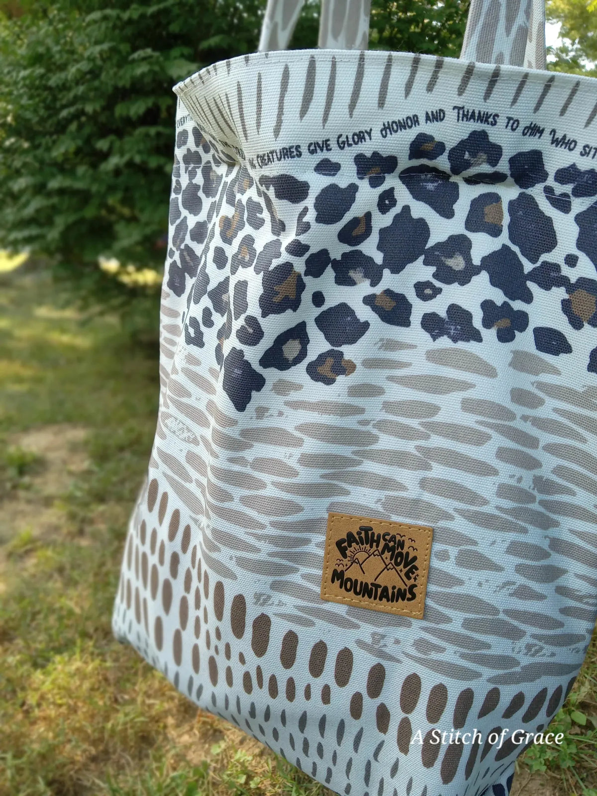 A tote bag with leopard print and a "Faith Can Move Mountains" patch.