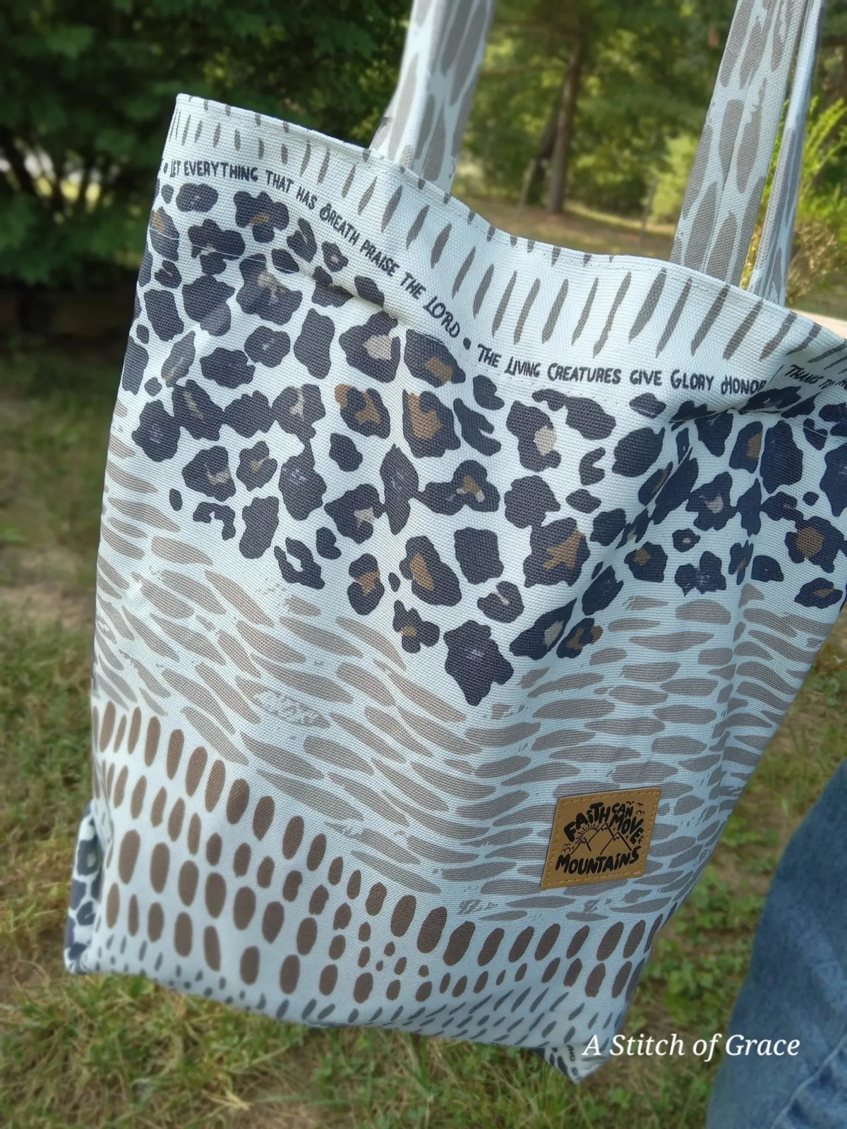 A tote bag with leopard print and a "Faith Can Move Mountains" patch.