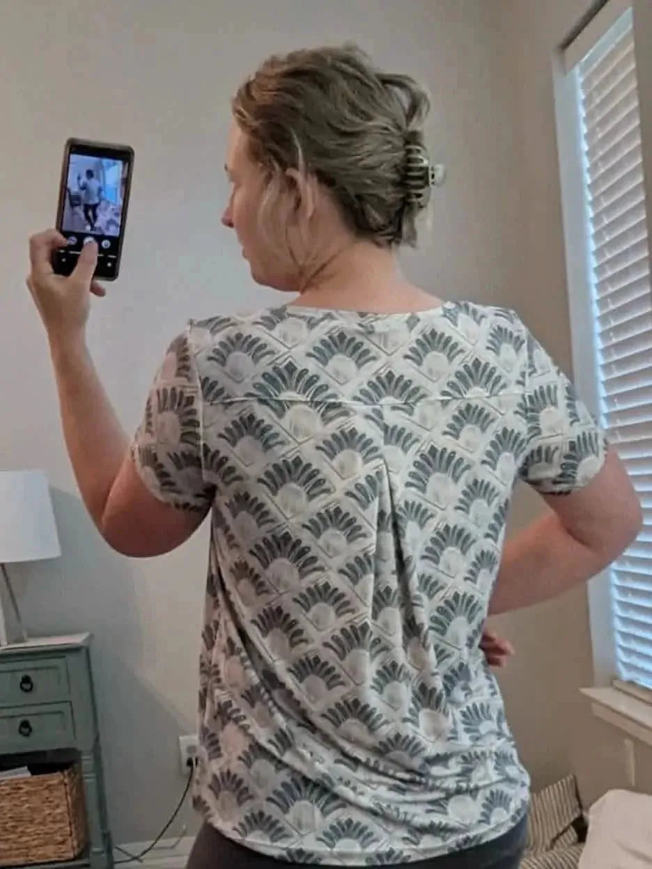 Back view of a short-sleeved women's top in gray Art Deco feather print fabric.