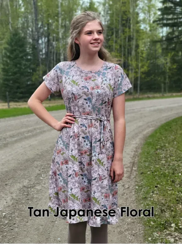 A young woman models a tan Japanese floral dress with a tie waist.