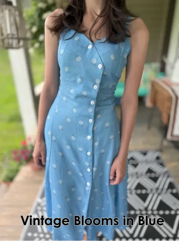 A woman models a blue rayon crepe dress with white polka dots and floral accents.