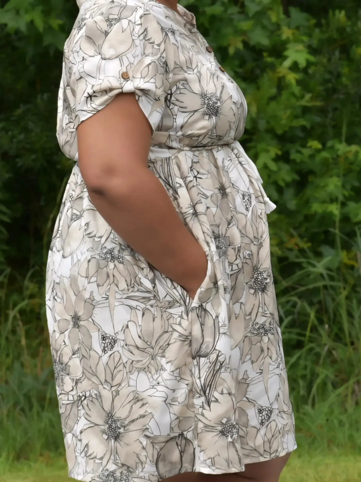 A person wearing a sepia sketch floral dress with pockets.