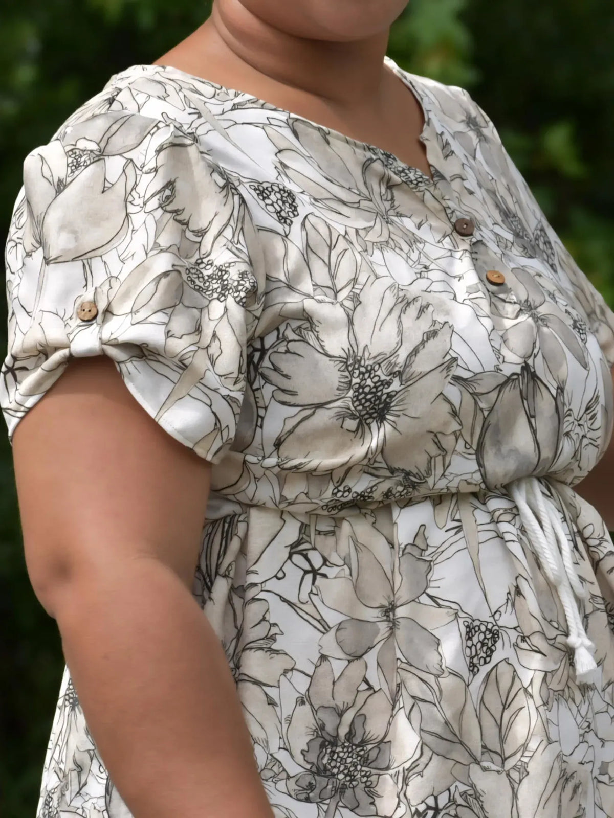 A person wearing a sepia sketch floral print dress with a drawstring waist.