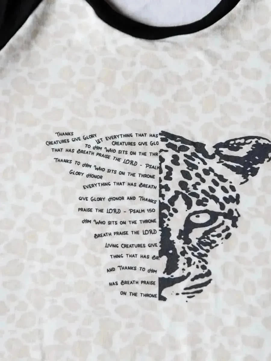 White t-shirt with black leopard print and overlaid Bible verse text.