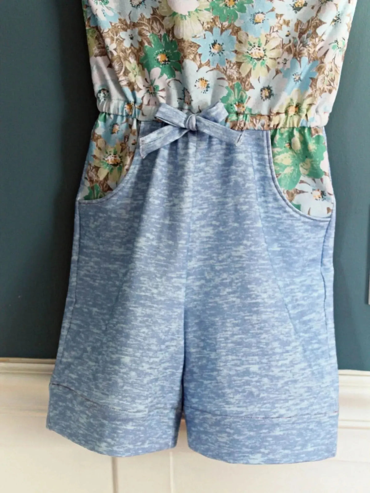 Light blue heather romper with a floral top and tie-front waist.