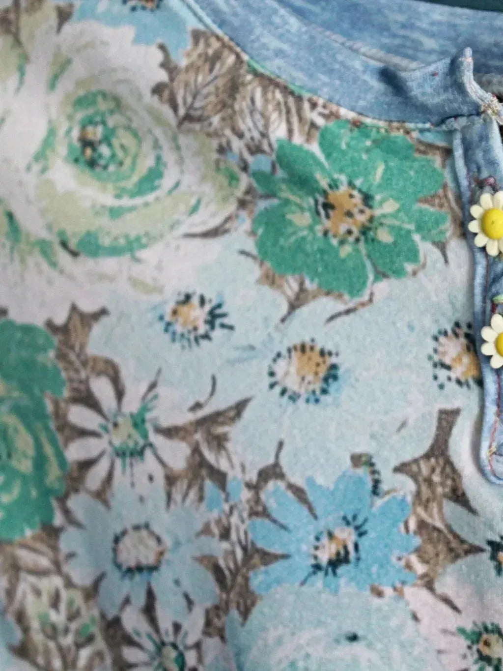 A floral print fabric with blue, green, and white flowers, featuring two daisy buttons.